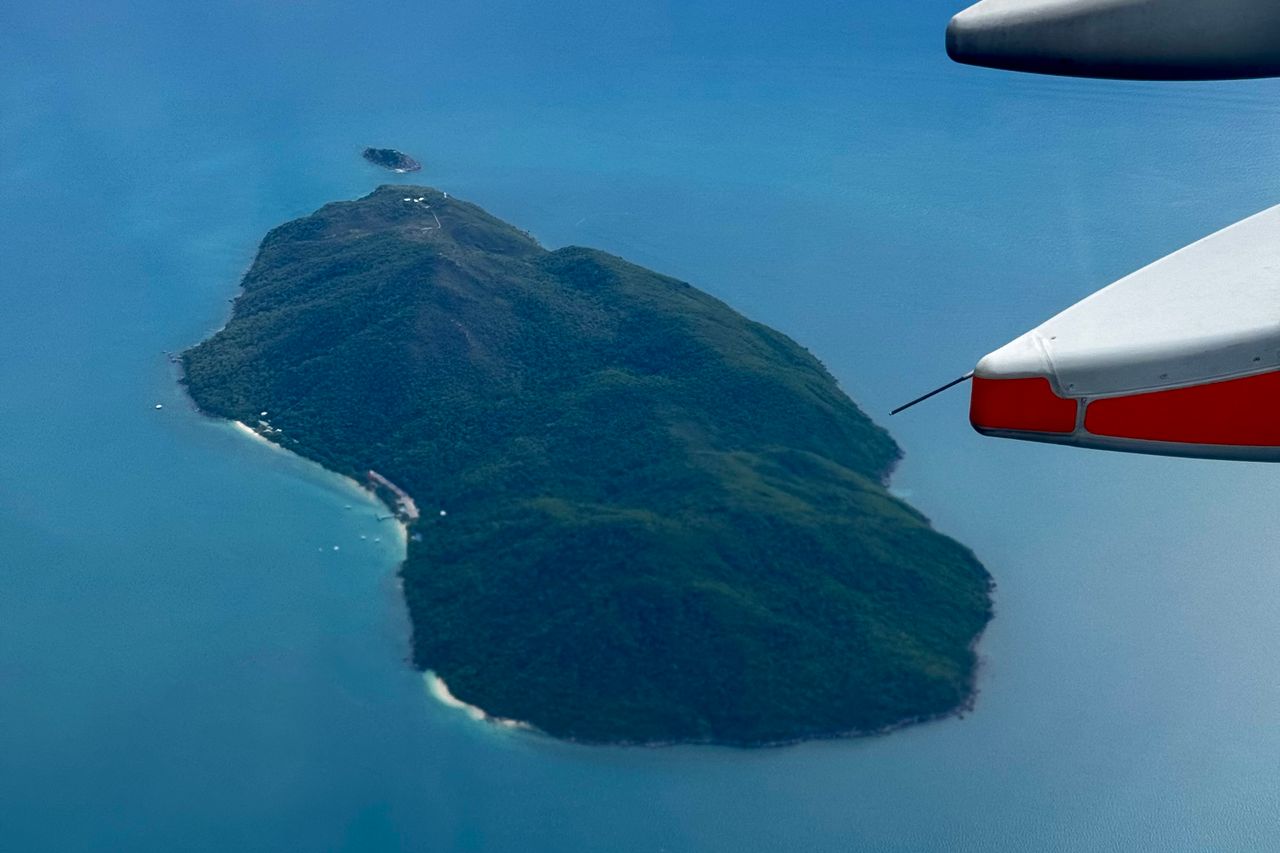 View of a tropical island and turquoise sea from an airplane window on approach