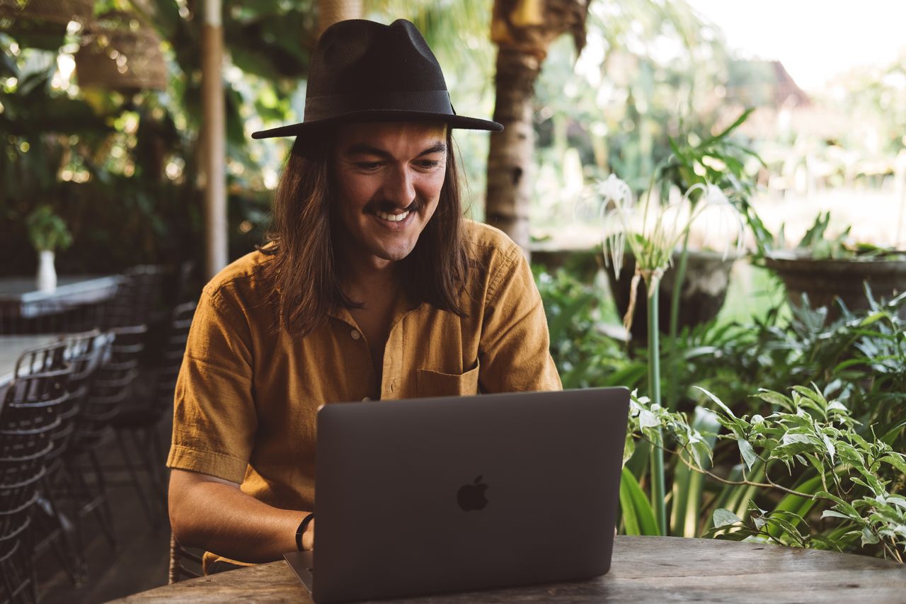 A remote worker on a laptop surrounded by tropical greenery, evocative of working from Langkawi