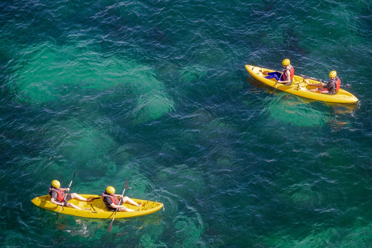 Aerial view of people kayaking on clear turquoise water, evocative of a Langkawi sea kayaking tour