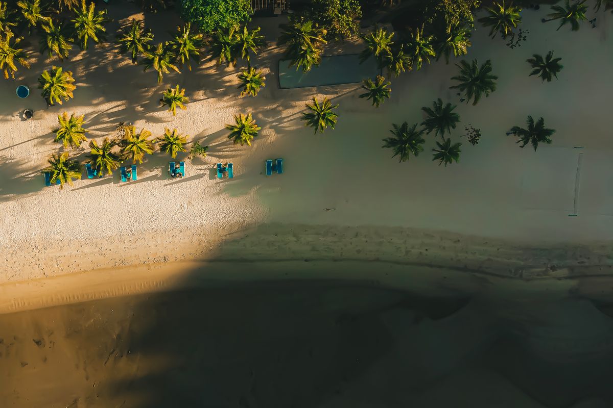 Aerial view of a palm-lined Langkawi beach and turquoise shallows